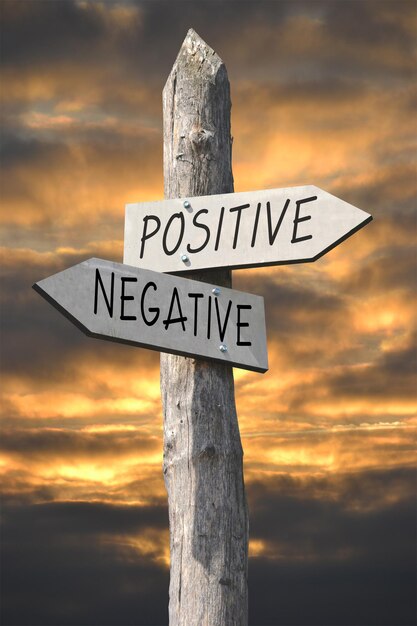 Photo positive or negative wooden signpost with two arrows and sunset sky