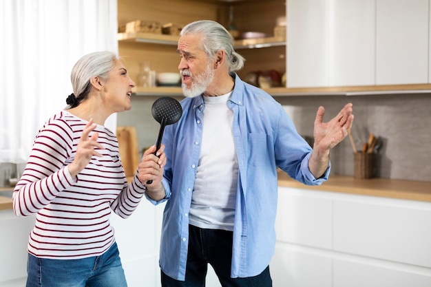 Positive Senior Couple Having Fun In Kitchen Interior Singing And Dancing