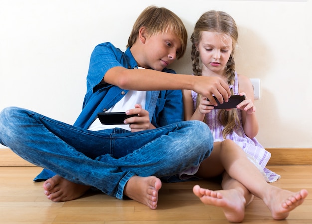 Positive siblings playing with phones