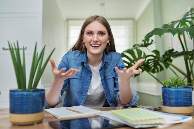 Positive smiling female university student talking looking at webcam at home