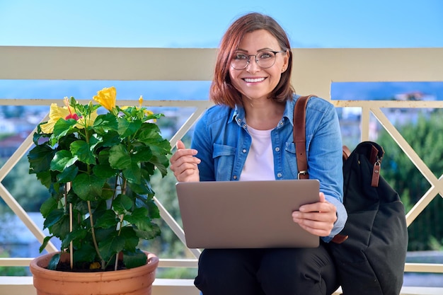 Positive smiling middleaged business woman with laptop outdoors