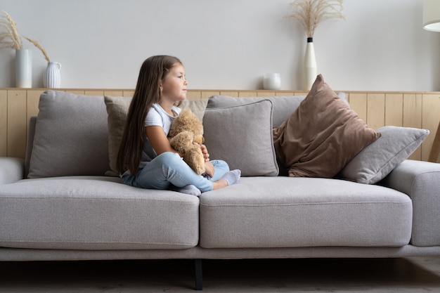 Positive smiling school girl lying on a couch.