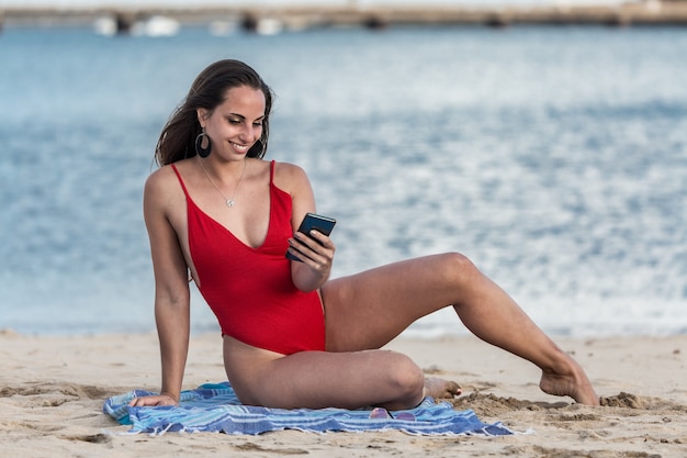 Positive woman using smartphone in weekend on beach