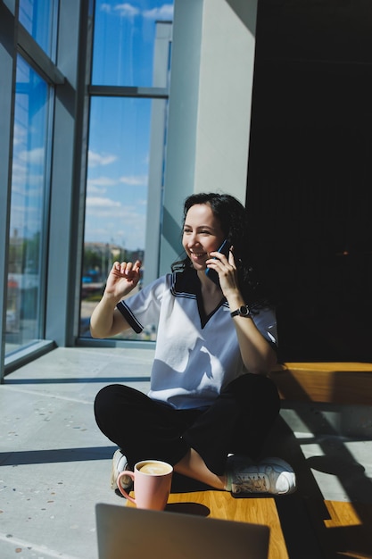 Positive woman with coffee working video call on laptop with webcams for communication happy with help woman watching comedy video on netbook in free time sitting in cafe