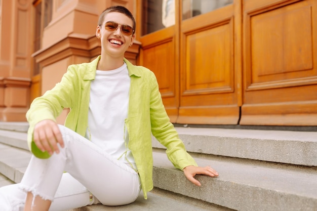 Photo positive woman with a short haircut and a green shirt walks and relaxes on the streets of the city