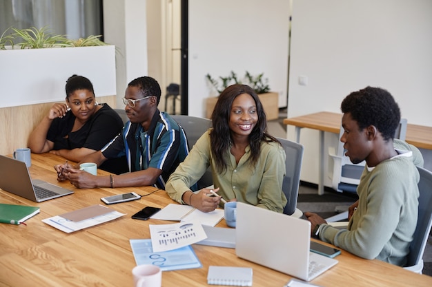 Positive young africanamerican business people talking at big meeting table