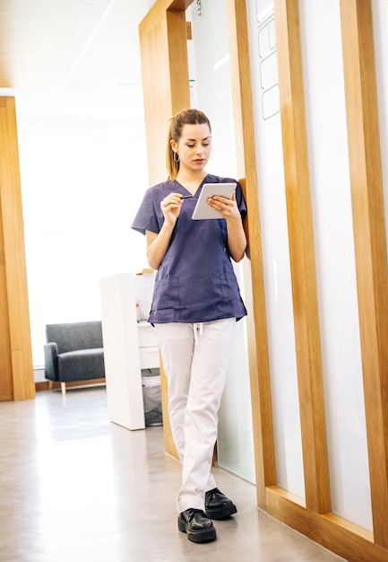 Positive young doctor using tablet in hospital