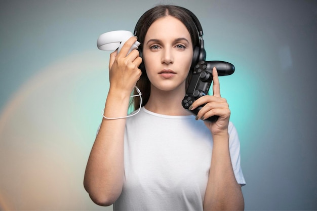 positive young female in casual clothes holding VR controller and console gamepad