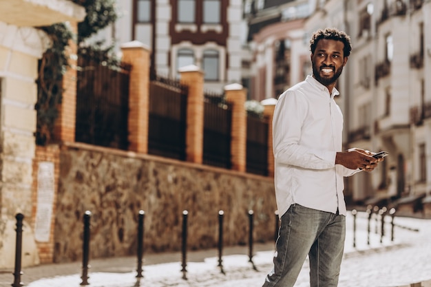 Positive young man in the street with smartphone looking away. Template banner