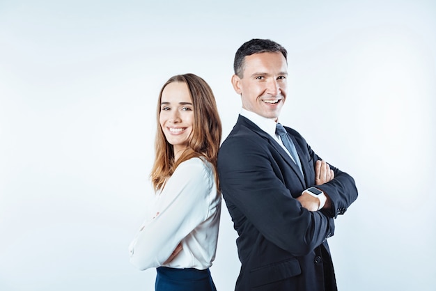 Positivity is the key to success. Waist up shot of friendly business coworkers looking into the camera with cheerful smiles on their faces while both posing with their hands crossed.