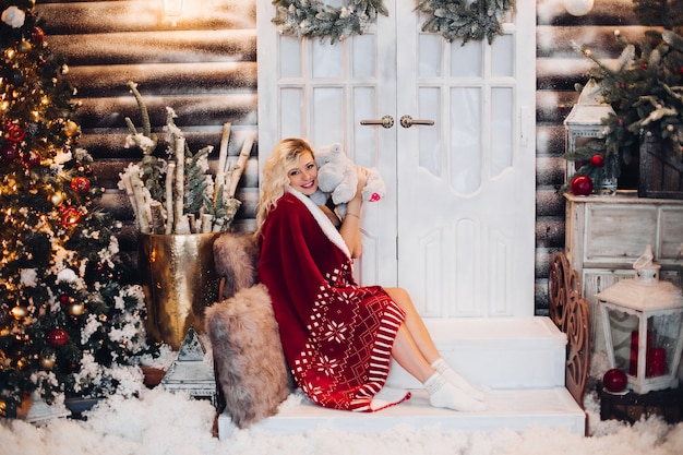 Positivity woman siitng on stairs wearing in plaid embracing teddy bear.