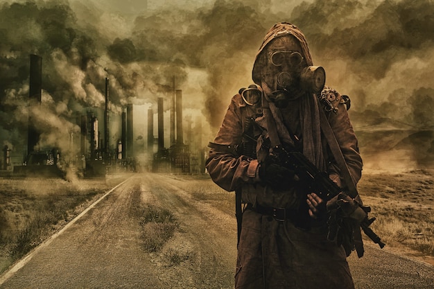 Post-apocalyptic air pollution. Survivor in tatters and gas mask on the background of pipes on abandoned road. Nature protection concept