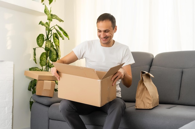 post, home and lifestyle concept - smiling man with cardboard boxes at home