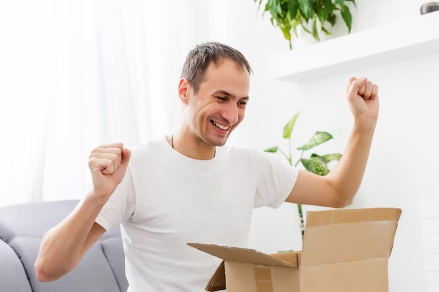 post, home and lifestyle concept - smiling man with cardboard boxes at home