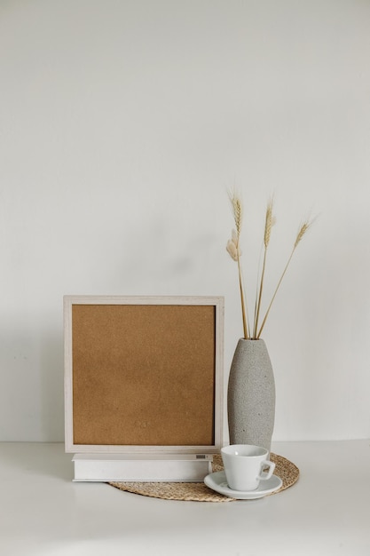 Poster art mockup with wooden square frame dried grass in vase and coffee cup in boho style decor