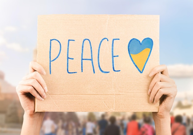 Photo a poster in the hands of a protester with the inscription peace in the city square