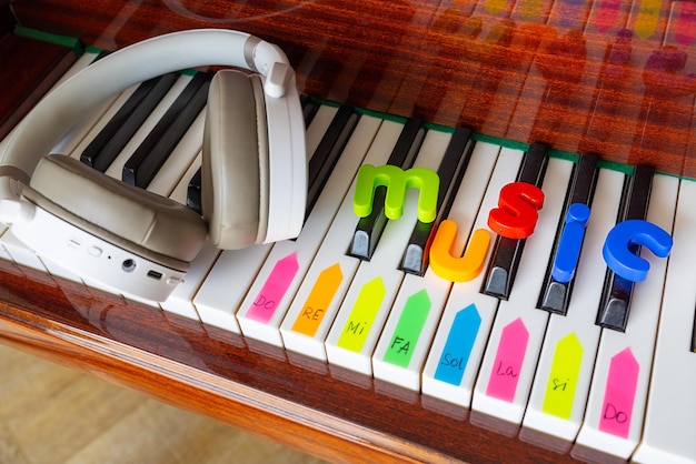 Poster with the word music letters musical notes and headphones on the piano closeup