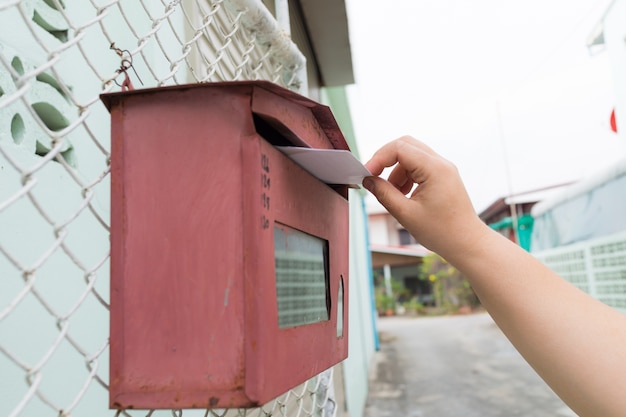 posting a letter to red british postbox on street, 