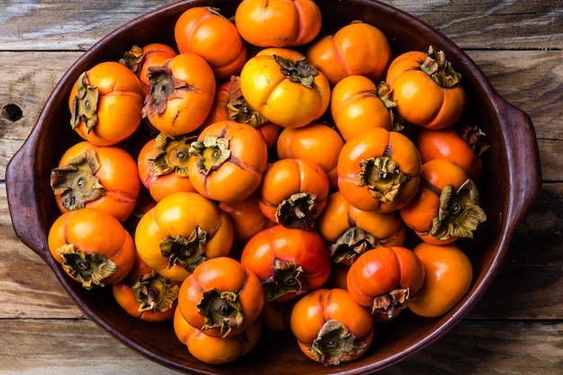 Pot of fresh fruits persimmon kaki on wooden background