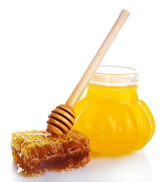 Pot of honey, wooden dipper and honeycomb isolated on white