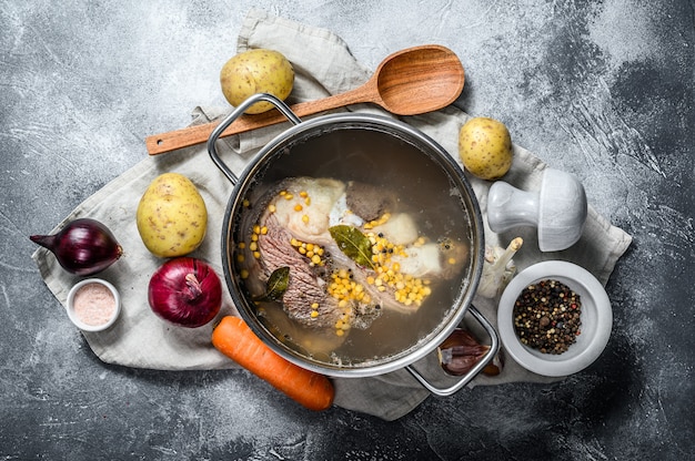 Pot with veal on the bone. Ingredients for soup, vegetables and spices. Top view