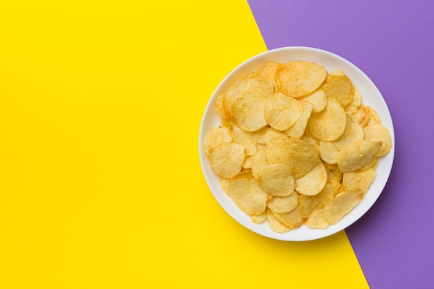 Potato chips on bowl isolated on colored background Delicious crispy potato chips in bowl Space for text Top view