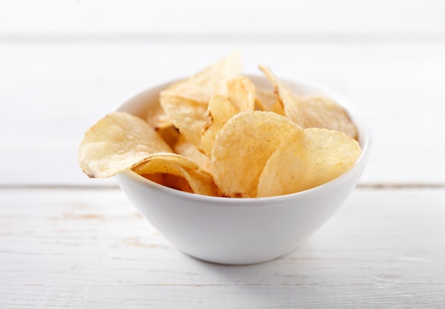 Potato chips on bowl on white background