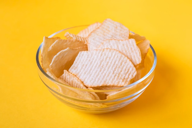 Potato chips in glass bowls on yellow background Junk unhealthy food chips party food fast food