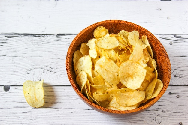 Potato chips snacks or crisps in wooden bowl against wooden background Pile of potato chips