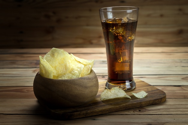 Potato chips with cola on a wooden background