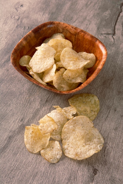 Potato chips on a wooden bowl over wood background