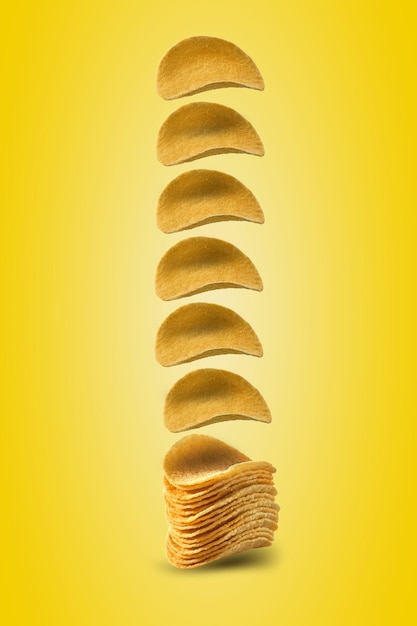 Potato crisps falling down against a yellow background with copy space for text or images Crispy palatable chips Advertising Closeup