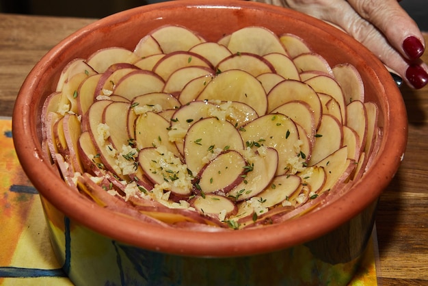 Potato gratin in flowershaped ceramic dish is ready for baking in the oven