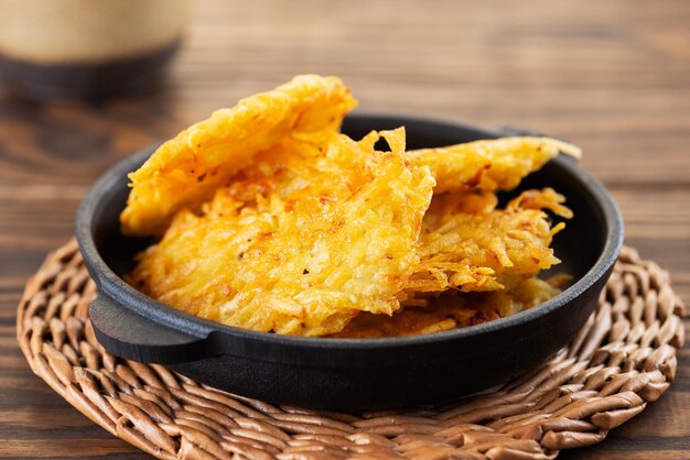 Potato pancakes draniki Latkes or Levivot in a cast iron frying pan on a wooden table Hanukkah food