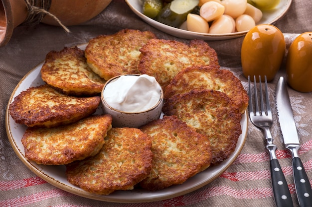 Potato pancakes with sour cream. The naitonal dish of Belarus. Draniki on a plate.