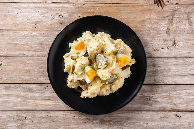 Potato salad with gherkins, egg and mustard on wooden table