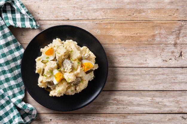 Potato salad with gherkins, egg and mustard on wooden table