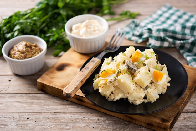 Potato salad with gherkins, egg and mustard on wooden table