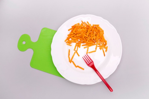 Potato straws on a white plate, top view