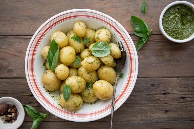 Potato. Tasty Young boiled potatoes with basil in white bowl on rustic wooden table