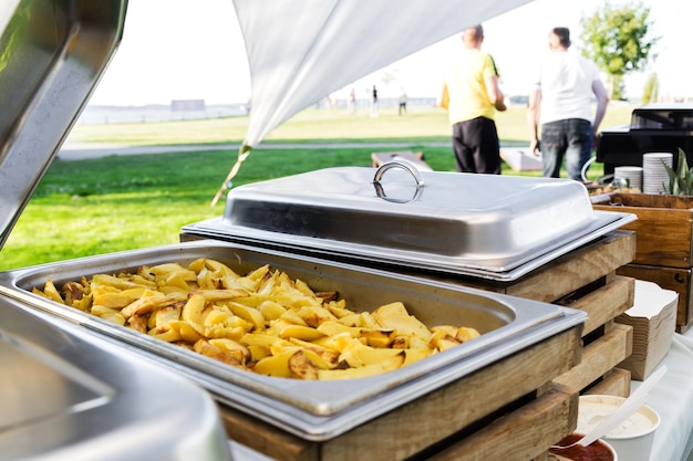 Potato wedges in a food warmer at a summer party Horizontal photo