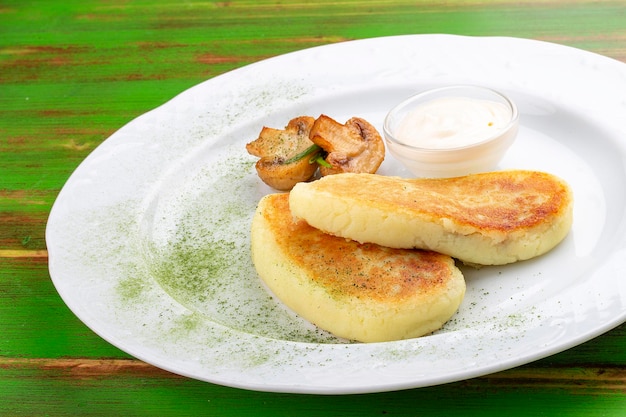 Potato zrazy with sour cream On a colored wooden background Vegetarian dish