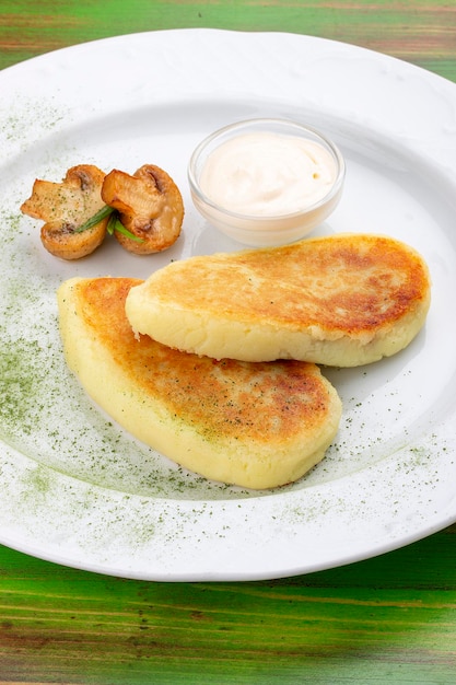 Potato zrazy with sour cream On a colored wooden background Vegetarian dish