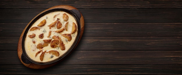 Potatoes baked in cheese in a pan on a wooden background