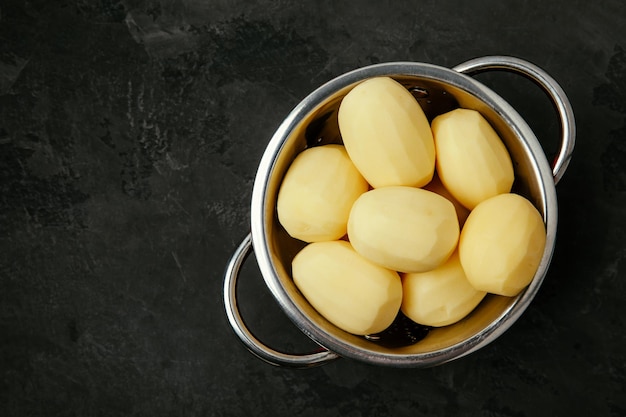 Potatoes Fresh raw peeled potatoes in colander on dark stone background Top view copy space