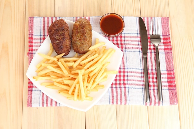 Potatoes fries with burgers on the plate on wooden background closeup