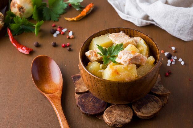 Potatoes stewed with chicken and vegetables in a wooden bowl.