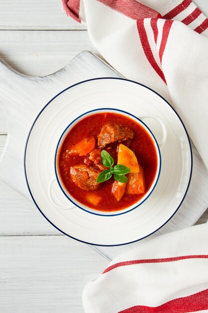 Potatoes stewed with meat in tomato sauce with spices and herbs no people on a white table