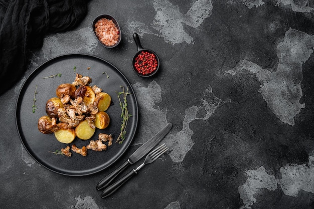 Potatoes with chanterelles set, on black dark stone table background, top view flat lay, with copy space for text