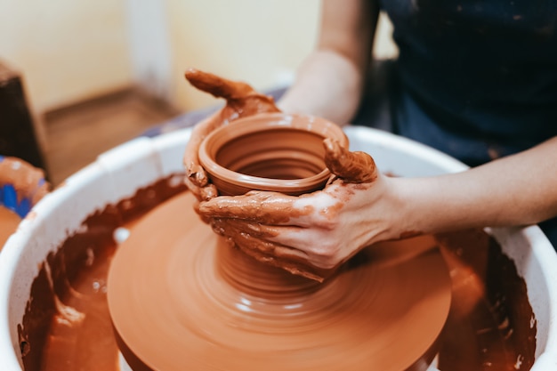 Potter behind the potter's wheel forms clay to create ceramic dishes